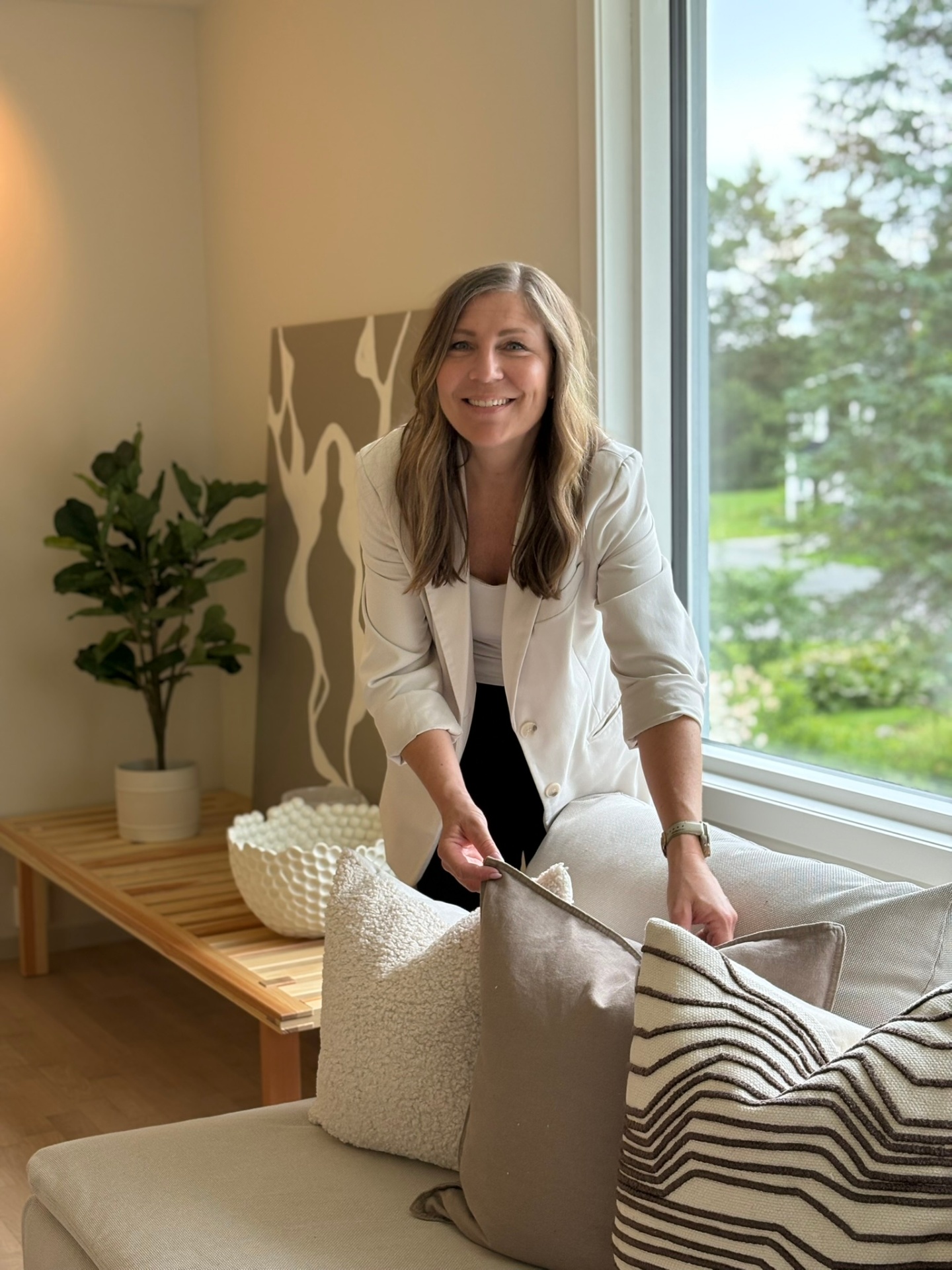 Linda legger puter på sofa, klar for visning
